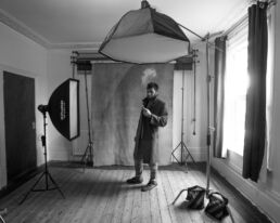 A behind the scenes image in black and white of a man vaping at a portrait session in north London