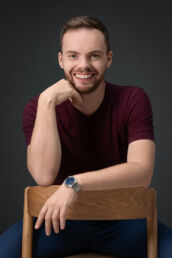 man sitting on chair backwards in t shirt and a blue watch on a london headhsots photoshoot