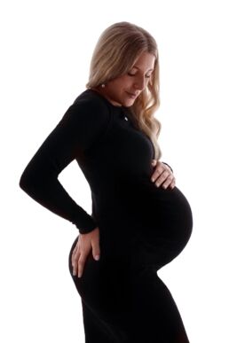 a pregnant woman wearing black against a white background with blonde hair