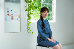 a London branding photoshoot of a user researcher in a workshop in a blue dress with plants.