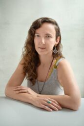 A london headshot photo of a woman's photoshoot with curly hair an earring and a yellow and grey top with pierced lip