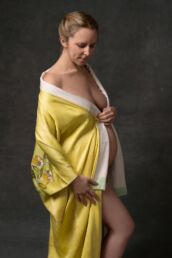 London maternity photo of a pregnant woman in a yellow robe with fine art lighting