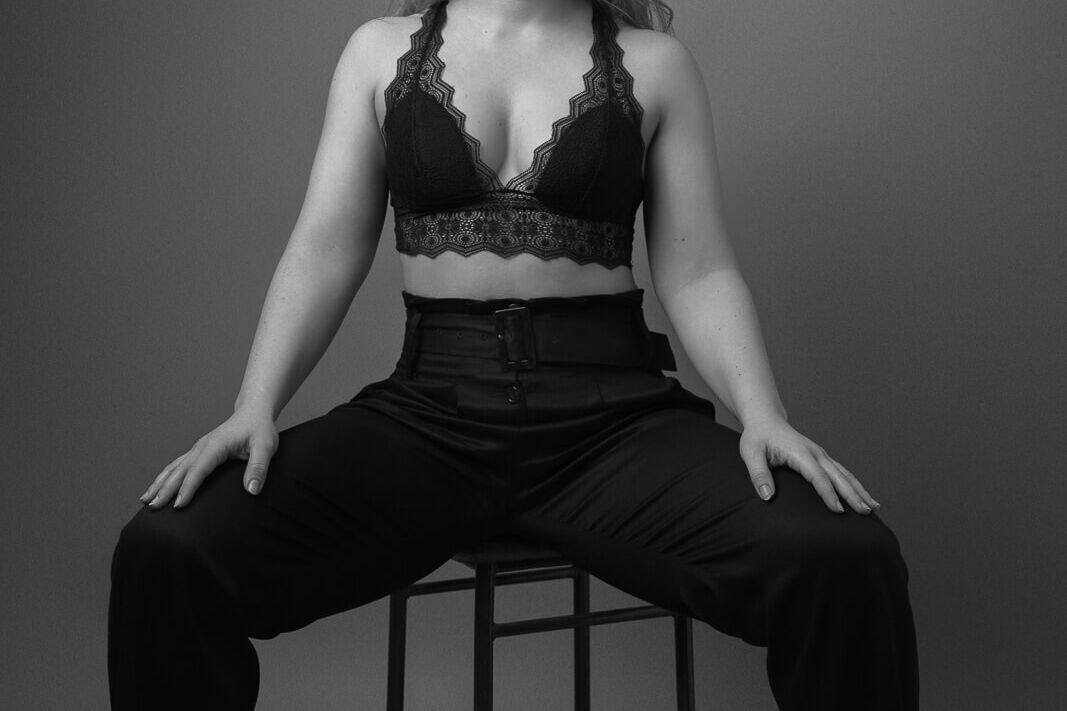 London boudoir photograph with a woman in a bralette and trousers in black and white