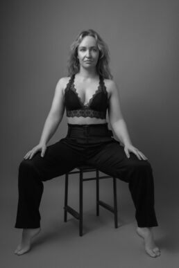 London boudoir photograph with a woman in a bralette and trousers in black and white