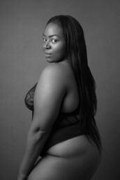 a woman in a lingerie body suit looking over her shoulder from a London boudoir photography photoshoot.