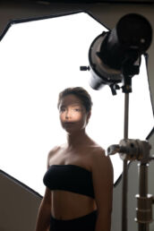 a woman in a black top against a photography studio light with creative light on the face
