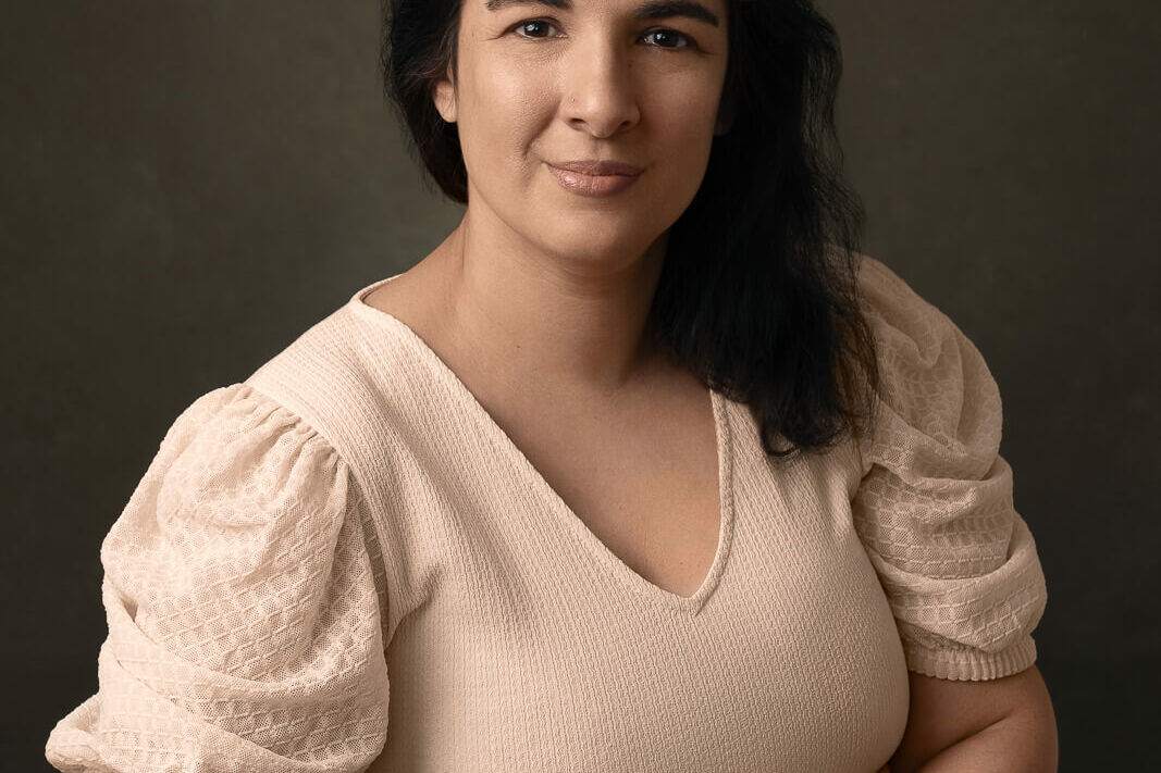 a female in a cream dress with warm vintage tones sitting at a wooden desk for a female portraits photography session