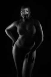 a black and white picture of a woman with bra and hoop earrings with rim lighting on a London boudoir photography photoshoot.