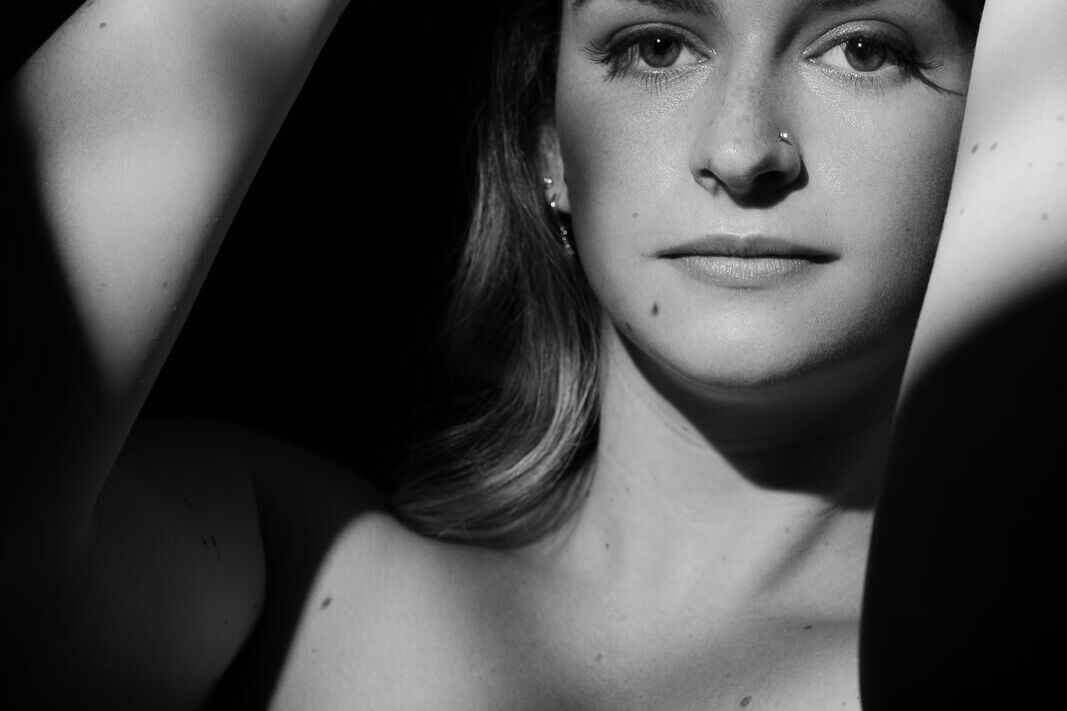 a woman in window light with the idea to love your body with a black and white boudoir photoshoot