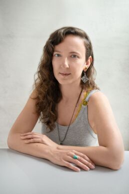 a woman with curly hair and arms folded in a grey top on a london portrait photography photoshoot