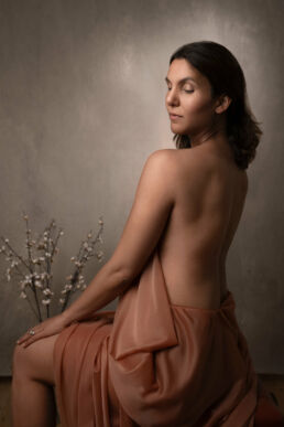 An Indian woman looking over her shoulder in drapery on a boudoir art london photoshoot.