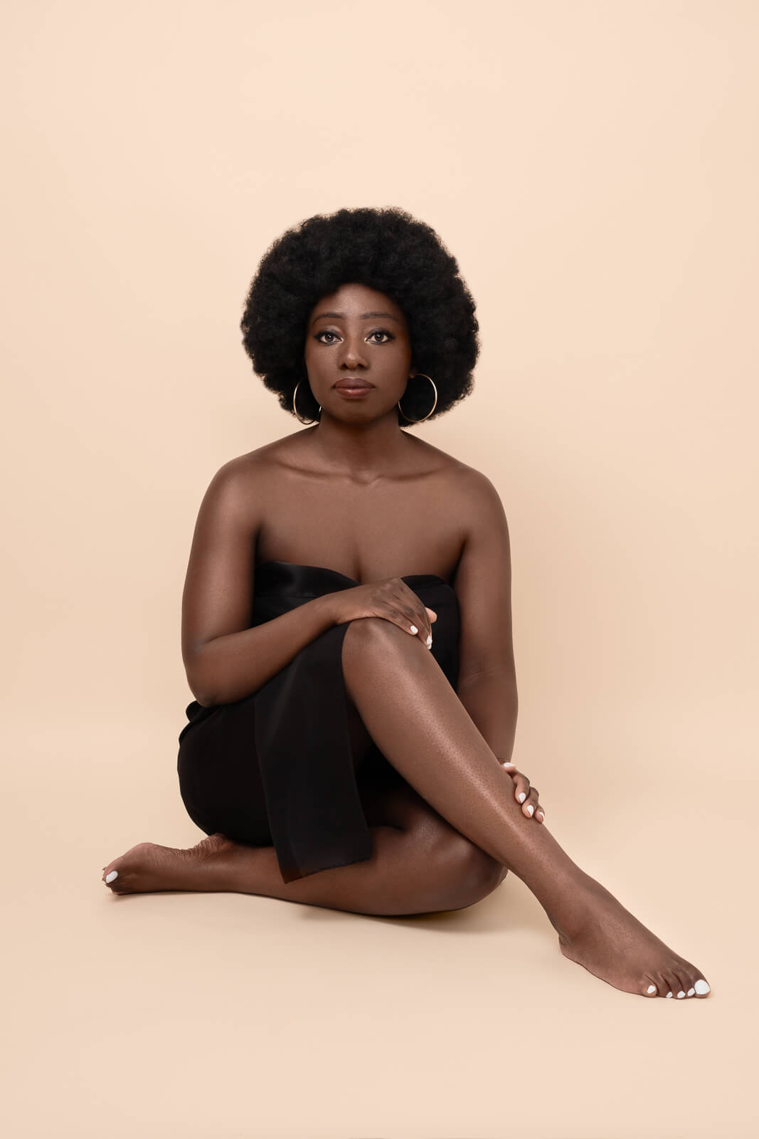 a black woman seated on the floor for boudoir poses at a London photoshoot
