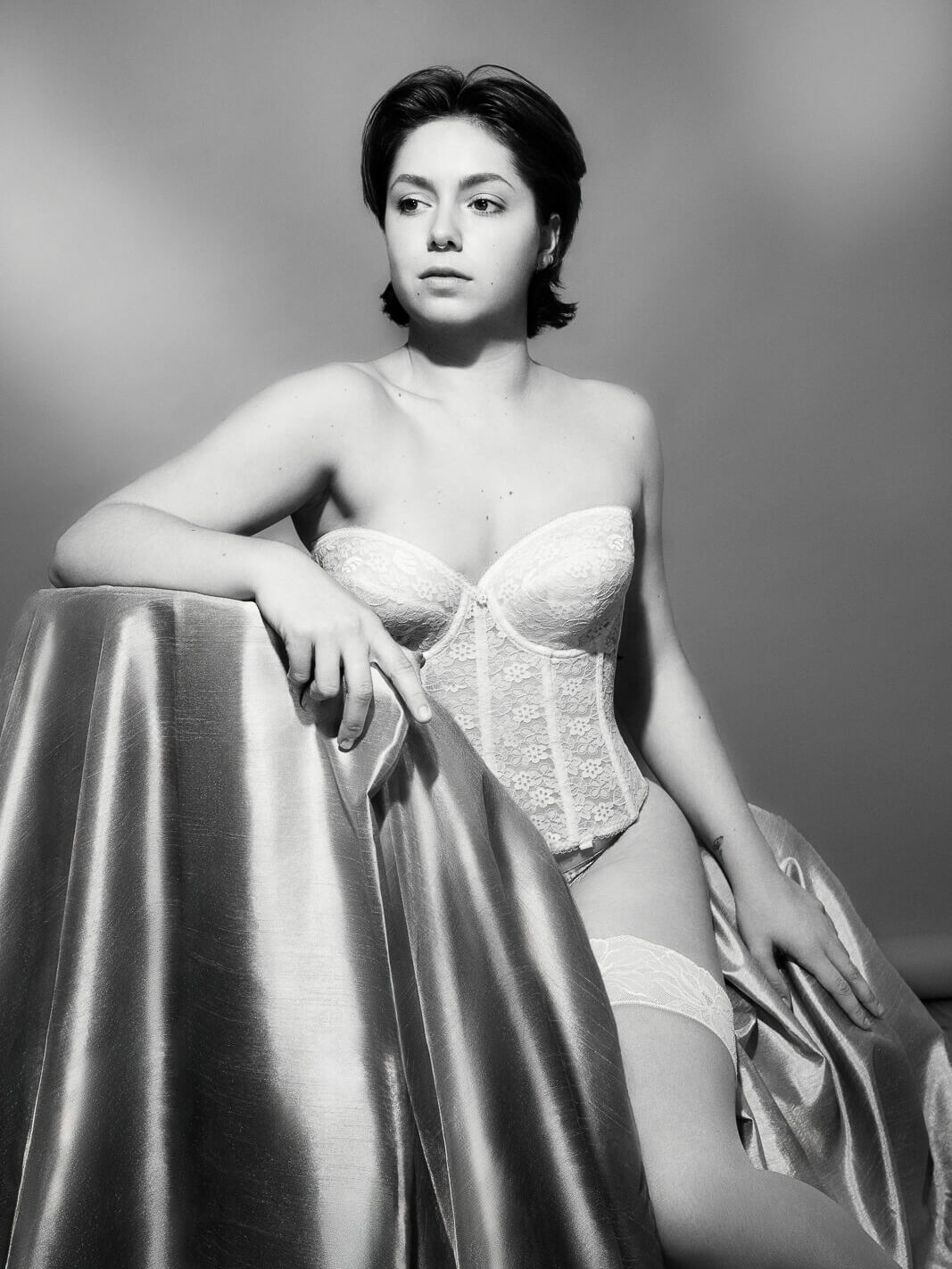a woman sat on satin curtains with old hollywood lighting makes for an exciting boudoir photo ideas.