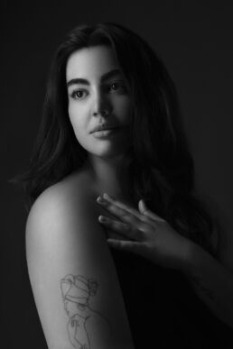 a woman touching her shoulder in a tasteful nude photo