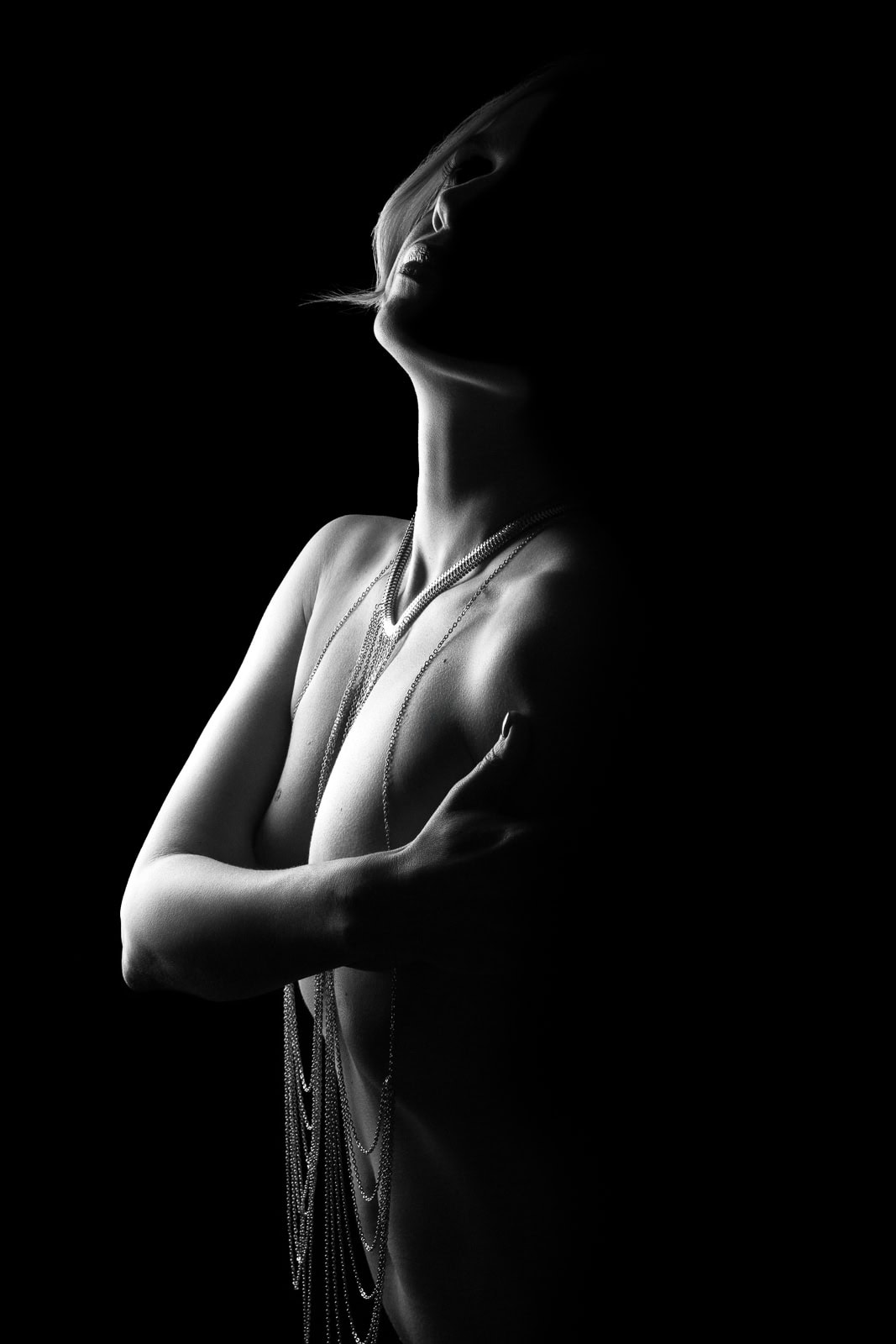 a woman in body chains wrapped in a light silhoette showing a tasteful nude photos style in london