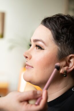 A woman having her boudoir make up looks done on a boudoir photoshoot