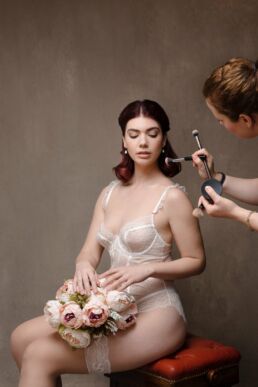 A woman in white lingerie holding flowers showing boudoir makeup looks on a London boudoir photoshoot