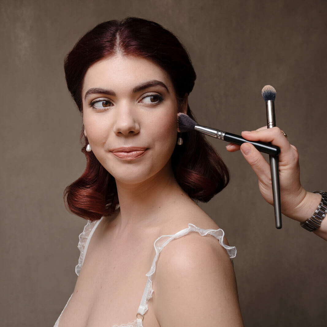 A woman in white lingerie with red hair showing boudoir makeup looks on a London boudoir photoshoot