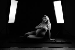a pregnant woman lying on the floor infront of studio lights on a london maternity photography photoshoot