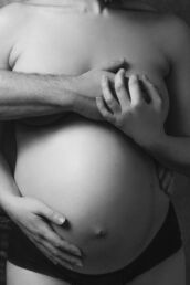 a couples London maternity photoshoot with man covering woman's breasts