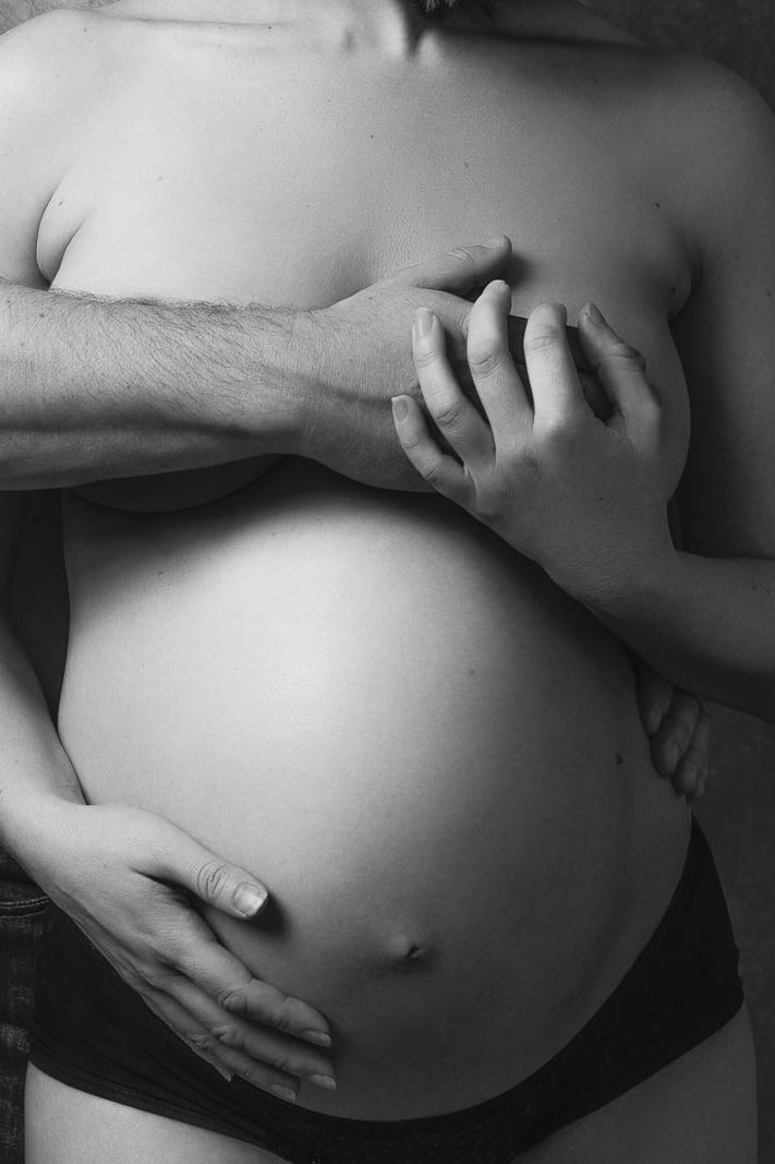 a couples London maternity photoshoot with man covering woman's breasts