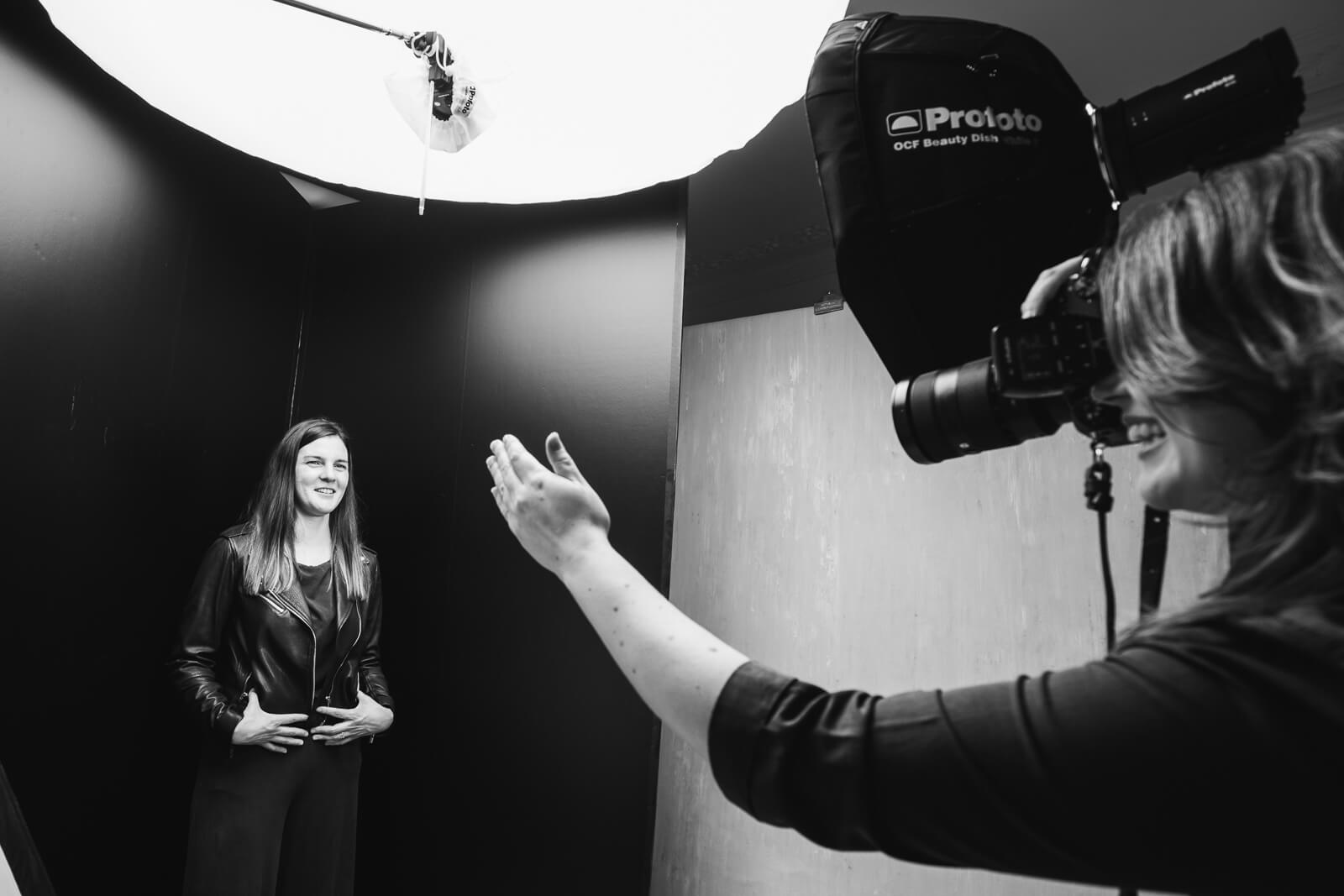 Behind the scenes of a photoshoot with photographer Siorna Ashby capturing a woman in a leather jacket smiling.