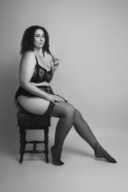 A curvy woman in lingerie seated on a boudoir photoshoot in London
