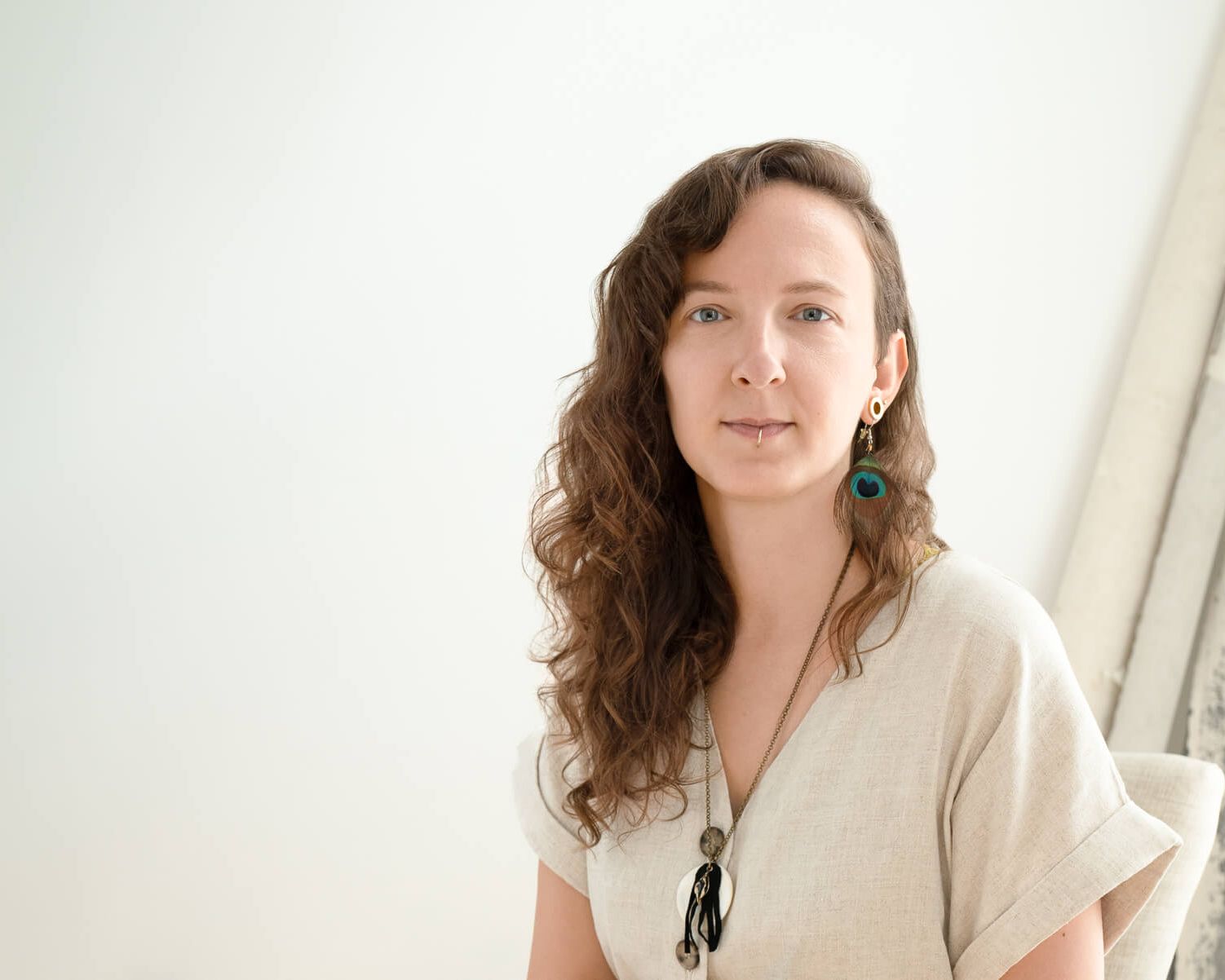 A woman with dark curly hair seated for a London headshot. The side window light shows how to take good headshots using side light