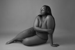 Curvy woman lying on the floor with posing support in black and white on a boudoir photography uk photoshoot