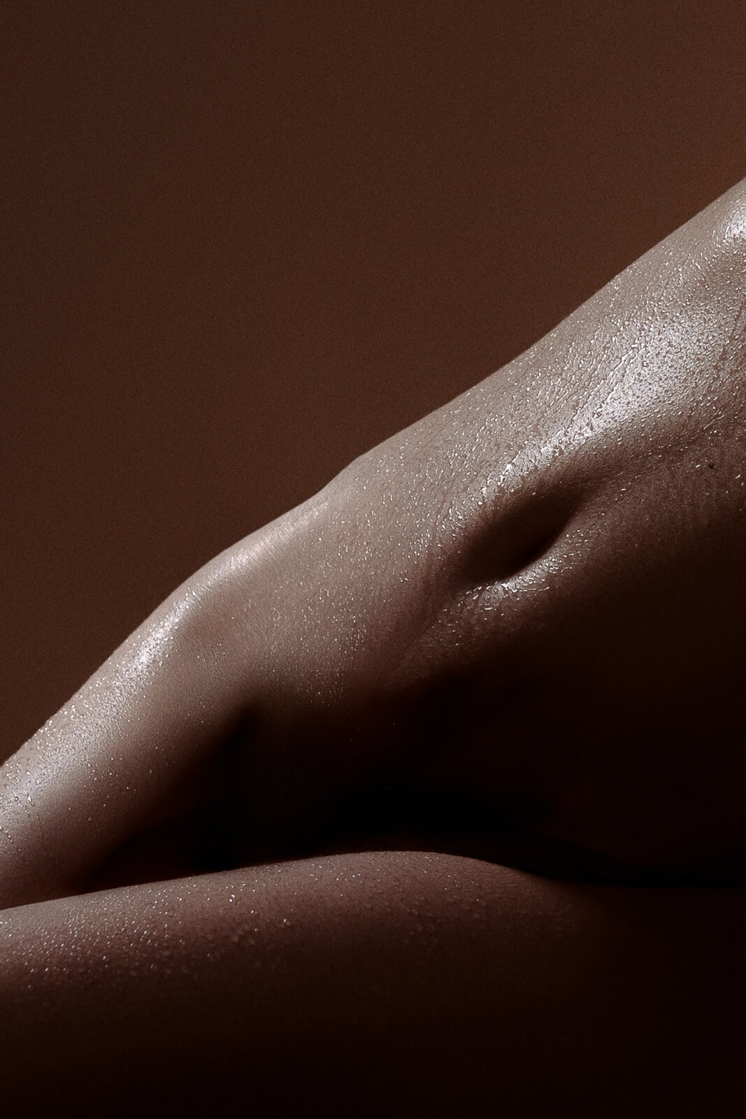 Close-up of a woman’s tummy stretched in golden sunset lighting, artistic intimate photograph with warm tones.