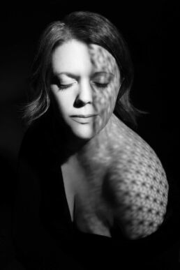 a woman with shadows on her face in a boudoir photography image