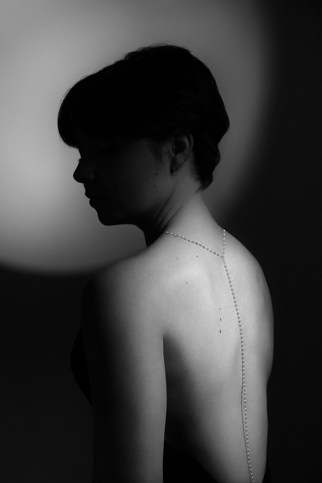 a woman with a pearl necklace down her back with old hollywood lighting from a collection of boudoir shots