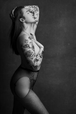 a woman wearing fishnet stockings with tattoos to showcase the best tights for boudoir