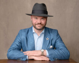 a man in a wide brimmed hat and blue jacket from headhsots in London