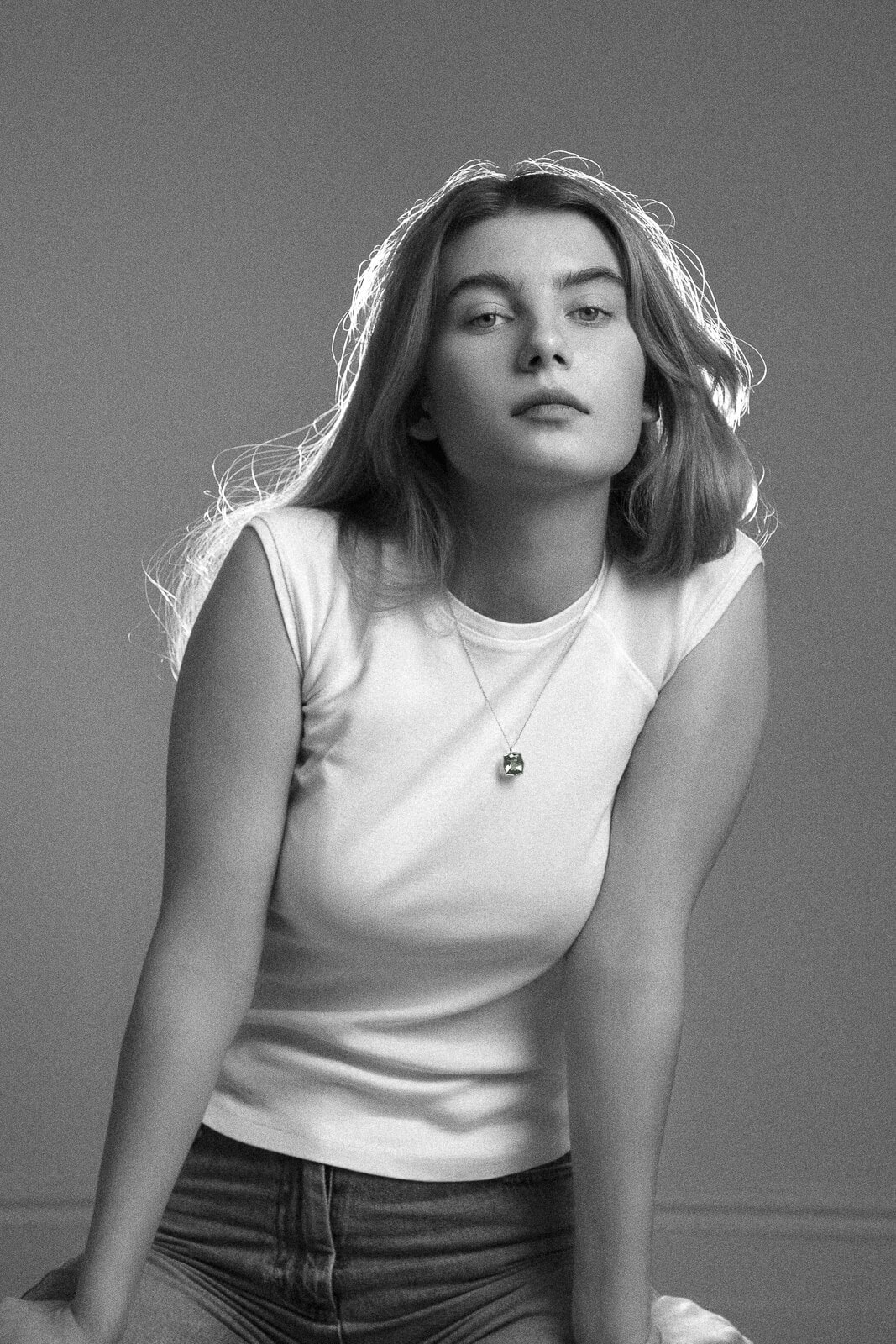 a woman with long hair in a white t shirt and jeans leaning forward in 90s vintage style