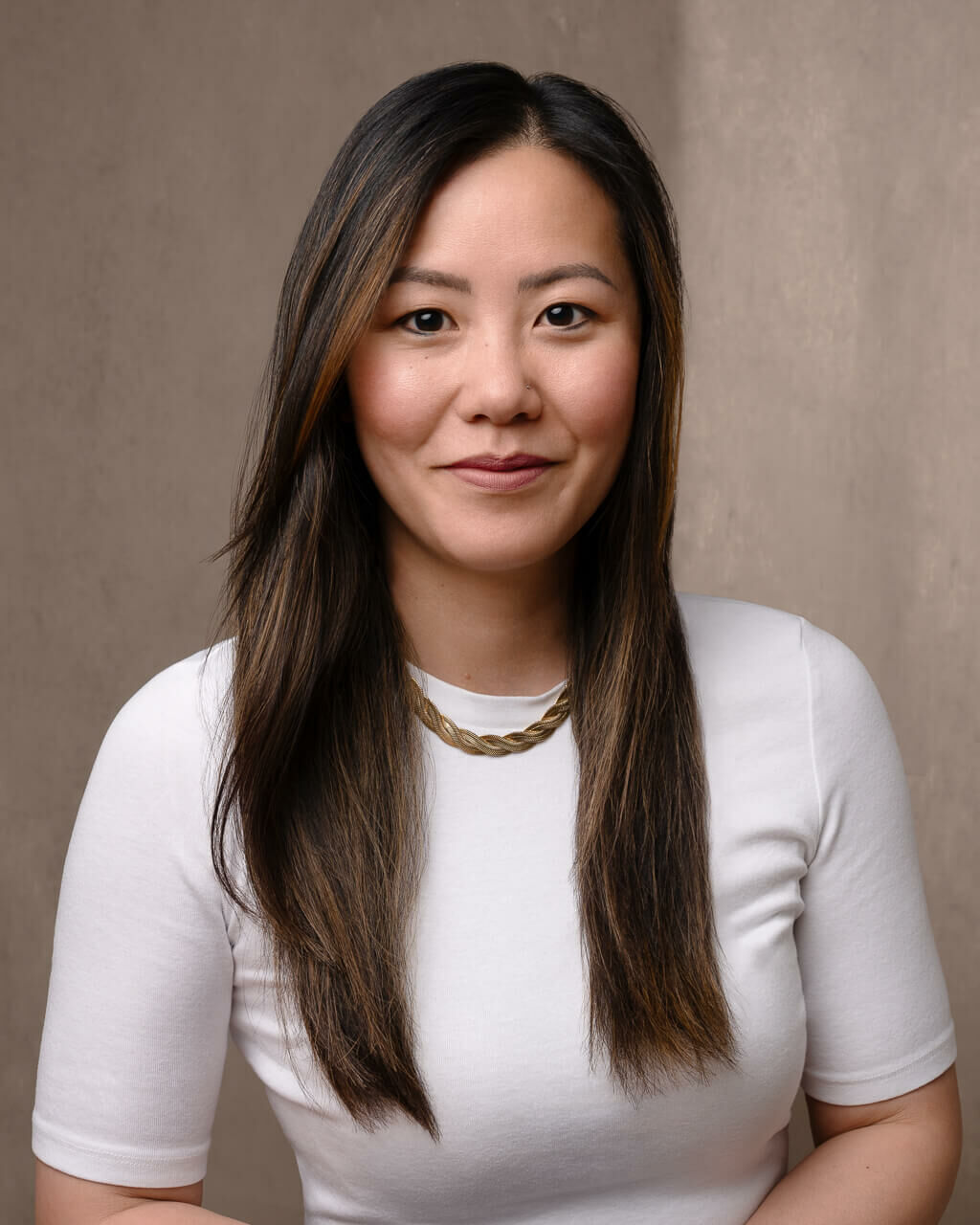 An asian woman in a white shirt and gold chain taken by a london headshot photographer