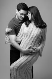 a couple posing for a maternity photoshoot in black and white