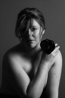 a female boudoir photographer holding a black rose on a london boudoir photography photoshoot
