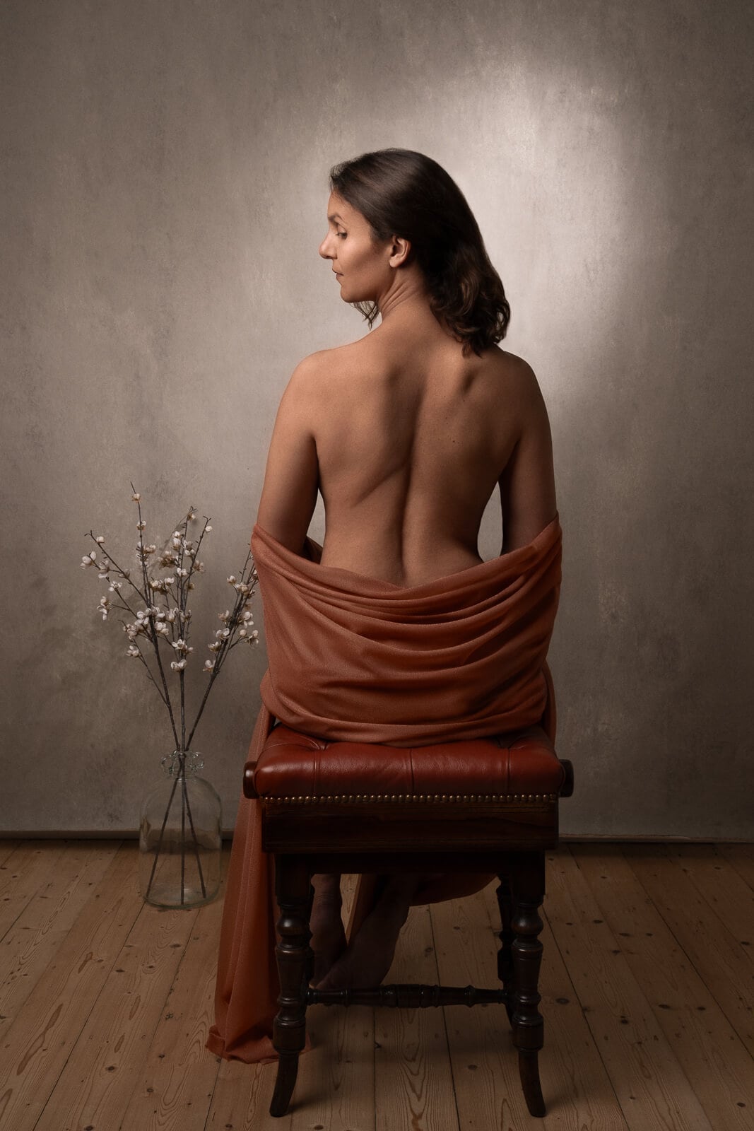 a south asian woman's back and seated in an orange cloth on a boudoir photoshoot for mums uk