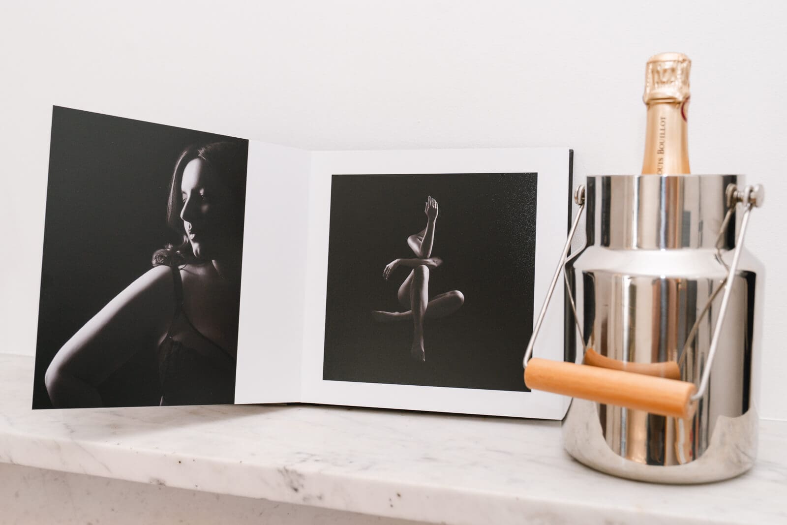 Open boudoir album with sparkling wine and a glass on the marble mantlepiece inside my London boudoir studio