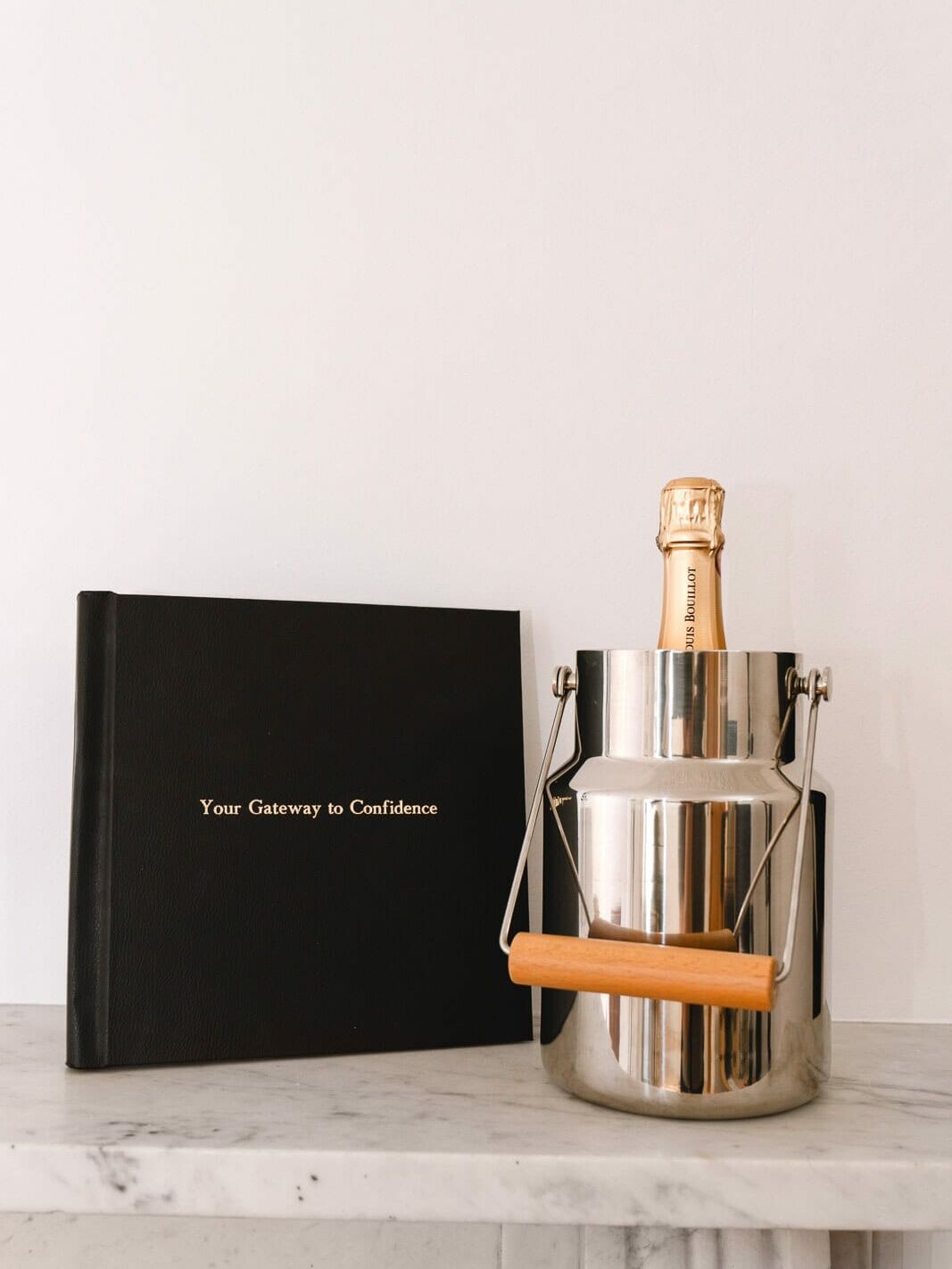 Closed boudoir album with sparkling wine and a glass on the mantlepiece inside my London boudoir studio