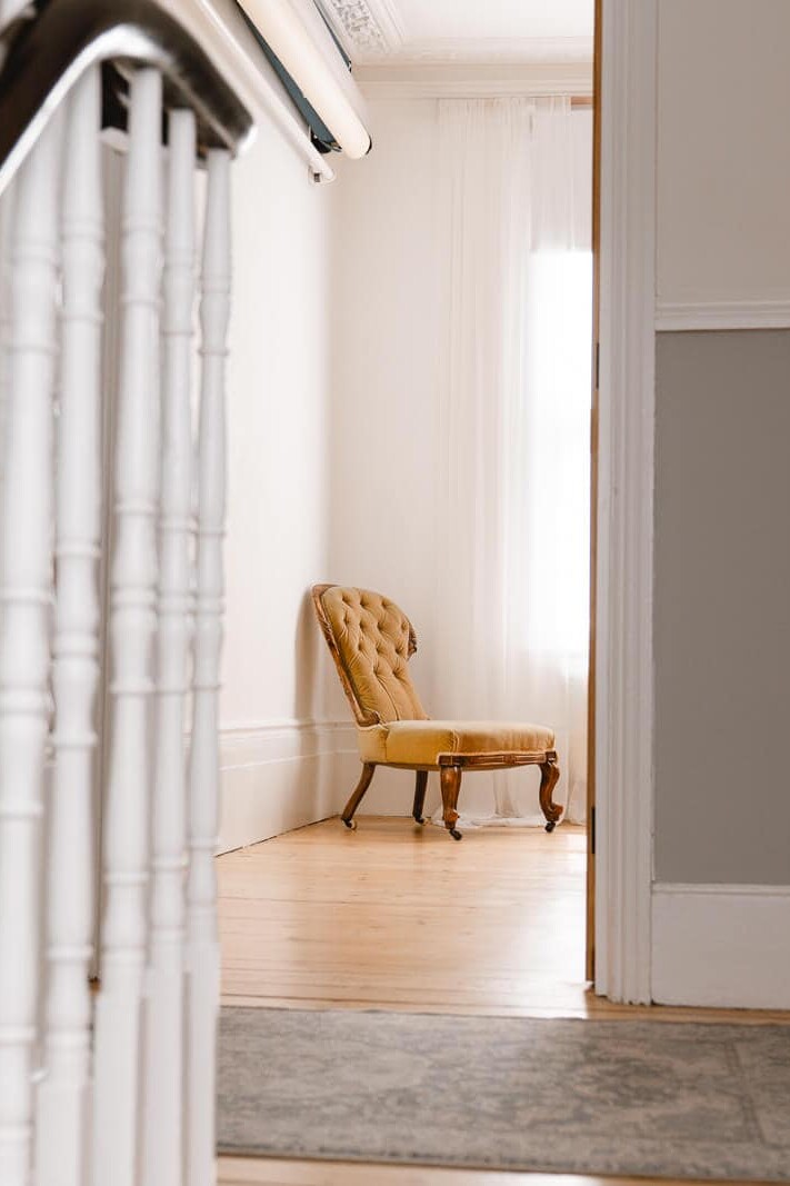 Vintage golden chair on wooden floors near a staircase, photographed at a low, voyeuristic angle inside my London boudoir studio.