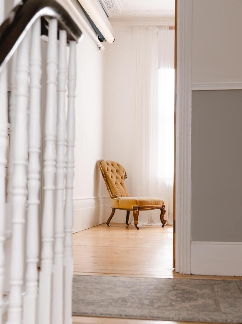 Vintage golden chair on wooden floors near a staircase, photographed at a low, voyeuristic angle inside my London boudoir studio.