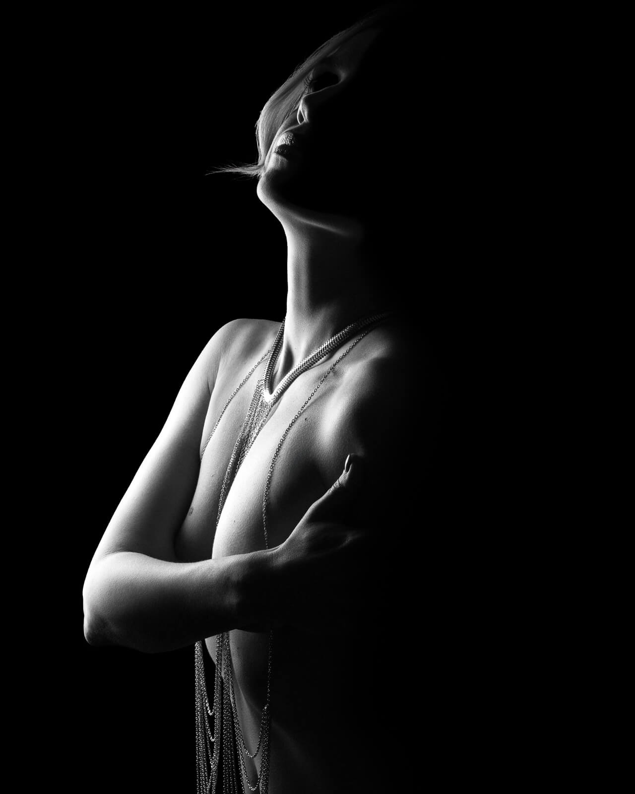 a woman in body chains with light silhouettes to answer london boudoir photography faq