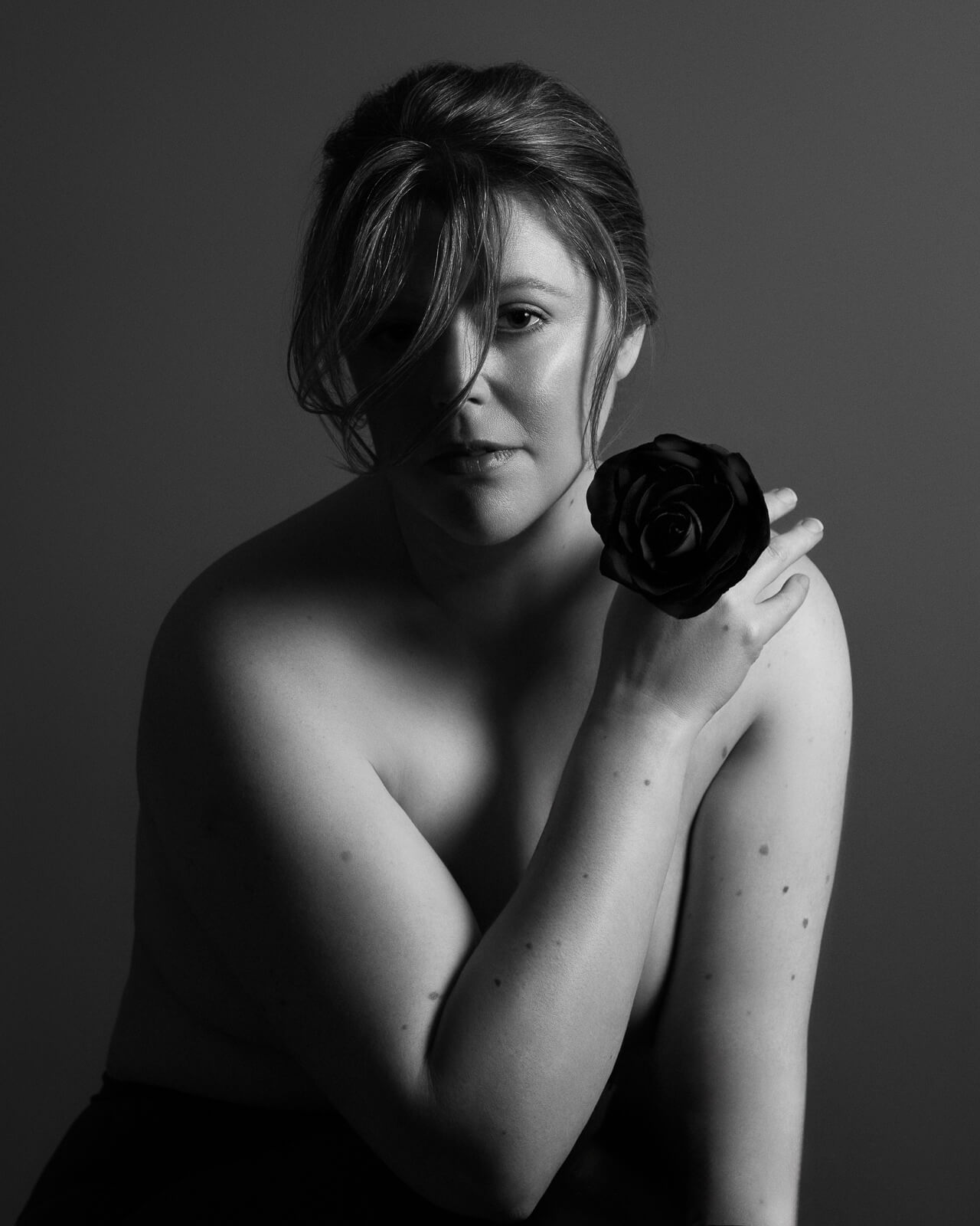 a female boudoir photographer holding a black rose
