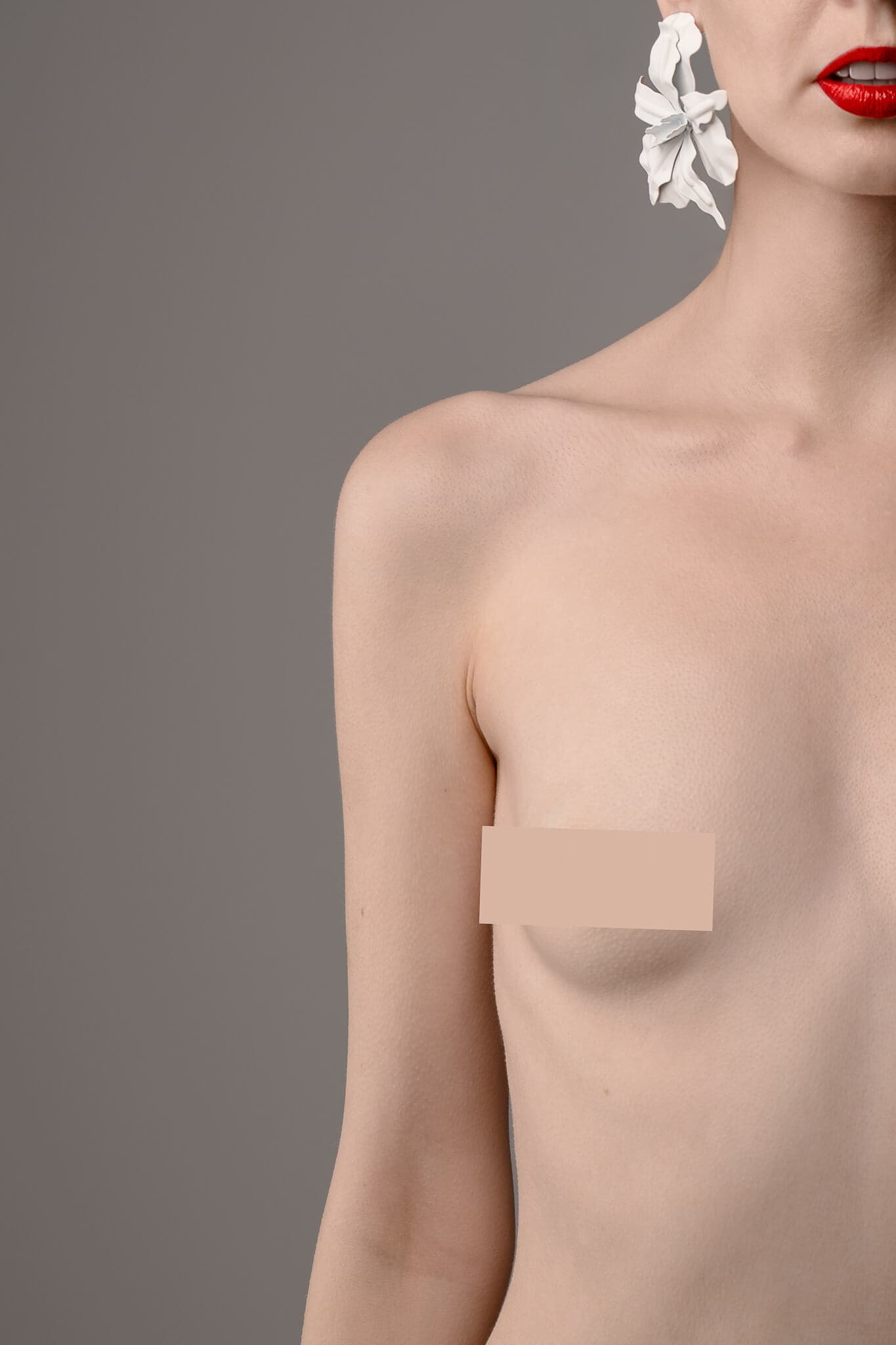 Colour portrait of a woman with red lipstick and white earrings, torso partly masked. Represents the female gaze in boudoir photography and empowerment through art.