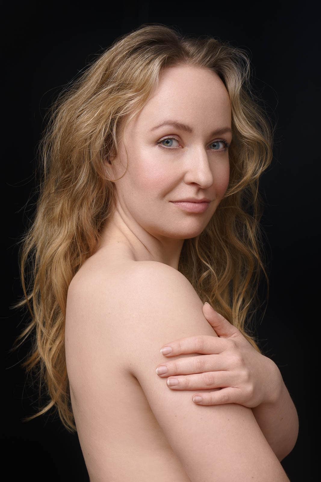 Soft and real boudoir portrait with bare shoulders in a London studio.