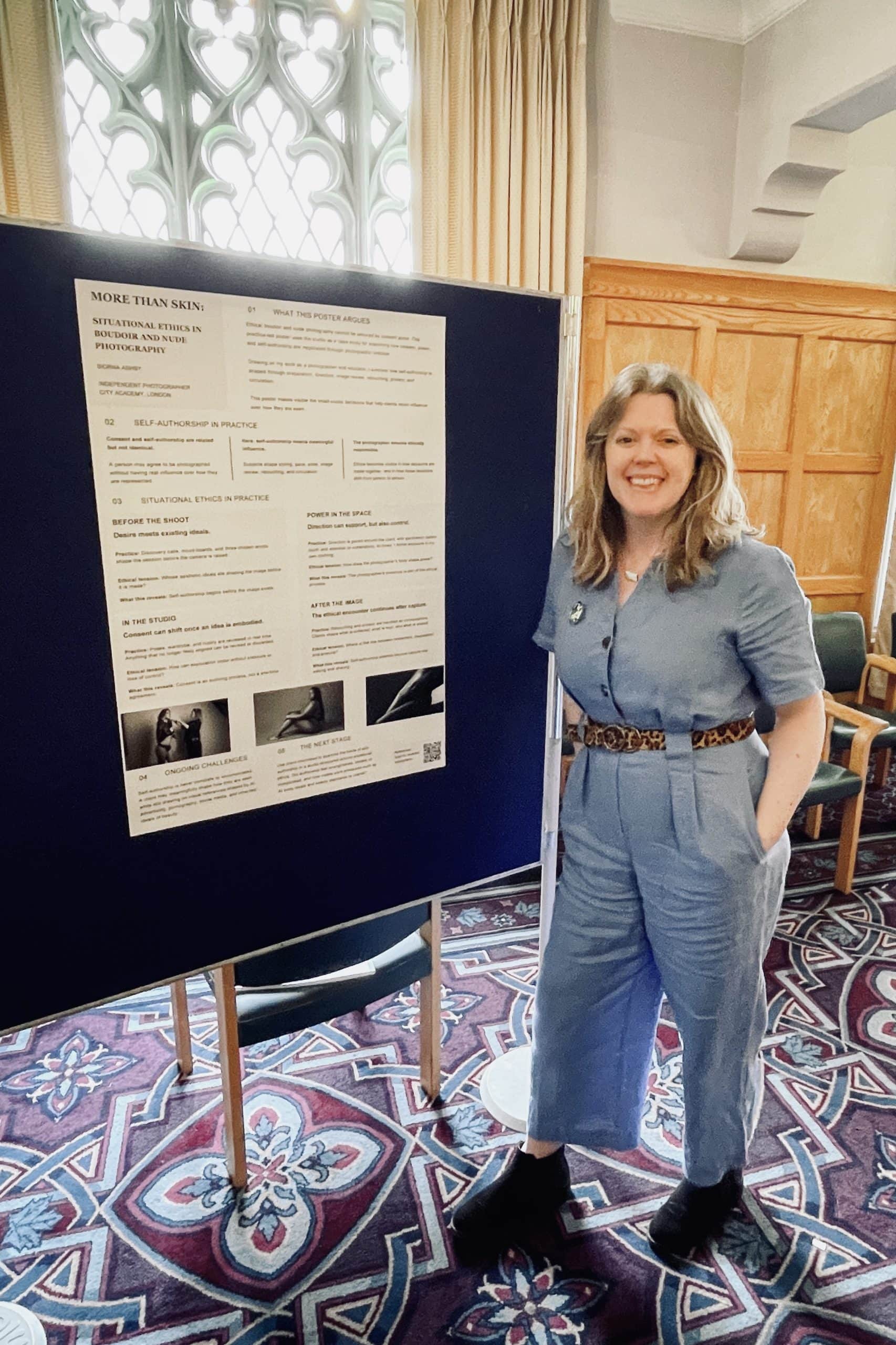Siorna Ashby standing beside her ethics poster on boudoir and nude photography at a photography symposium.
