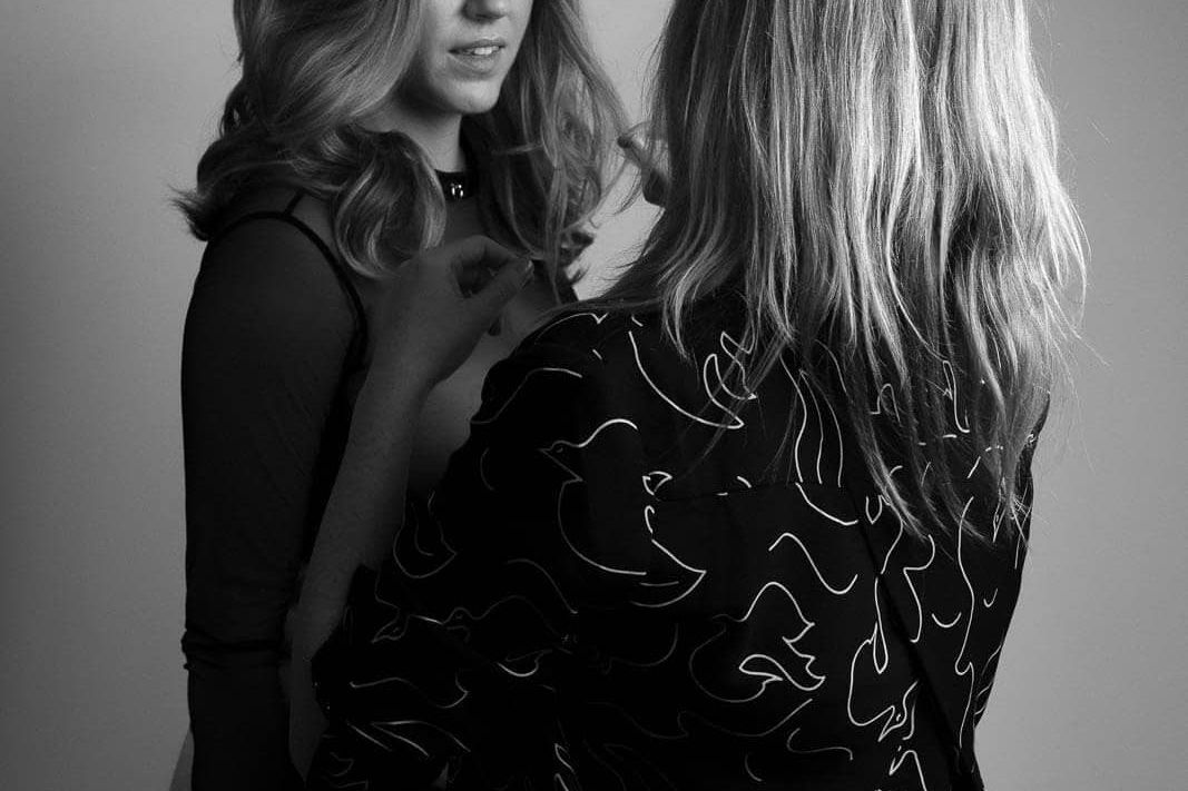 Behind-the-scenes black and white image of a boudoir photographer gently directing a client during an ethical boudoir studio photoshoot.
