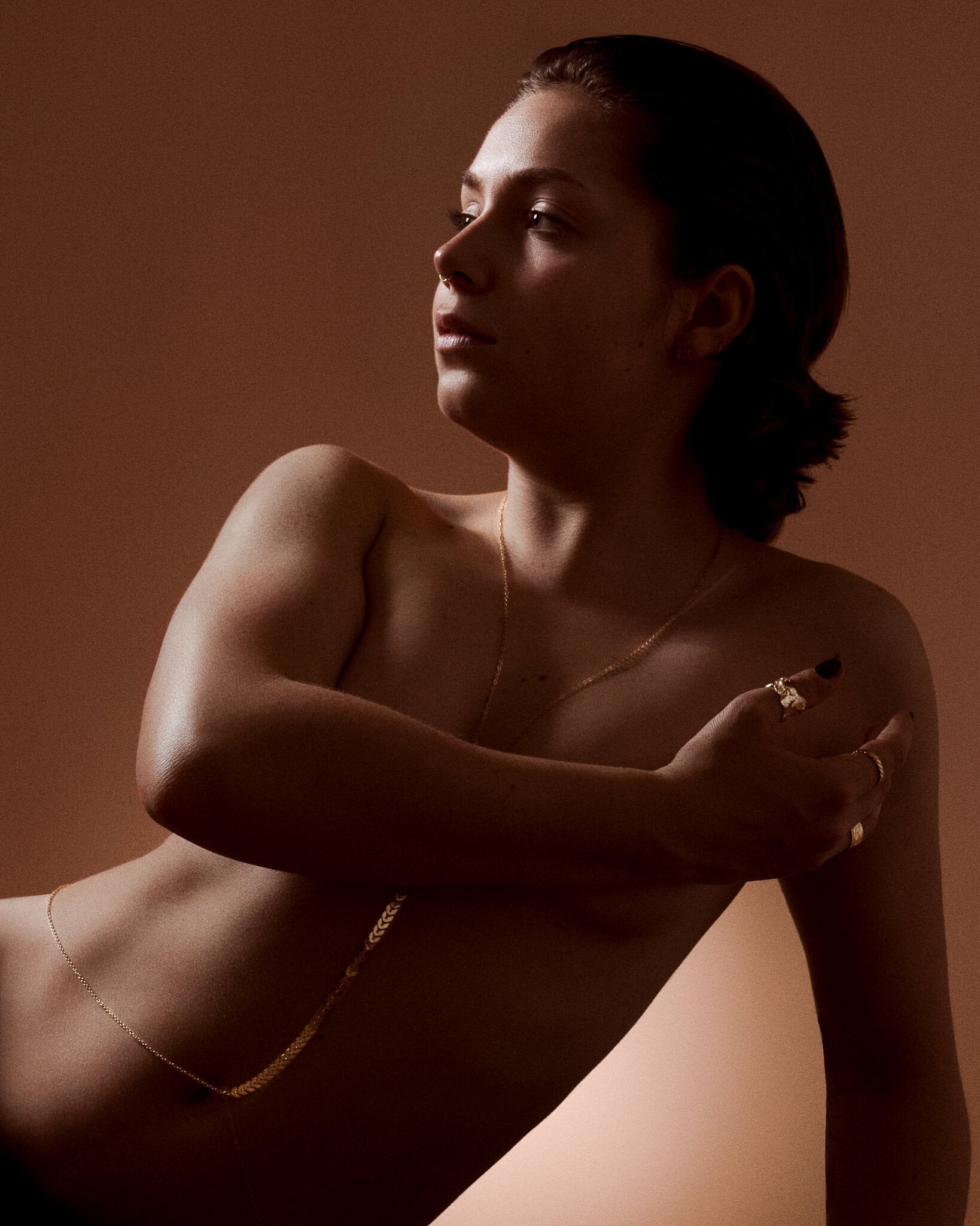 Artistic reclining portrait of a woman photographed with warm studio lighting by a London portrait photographer.